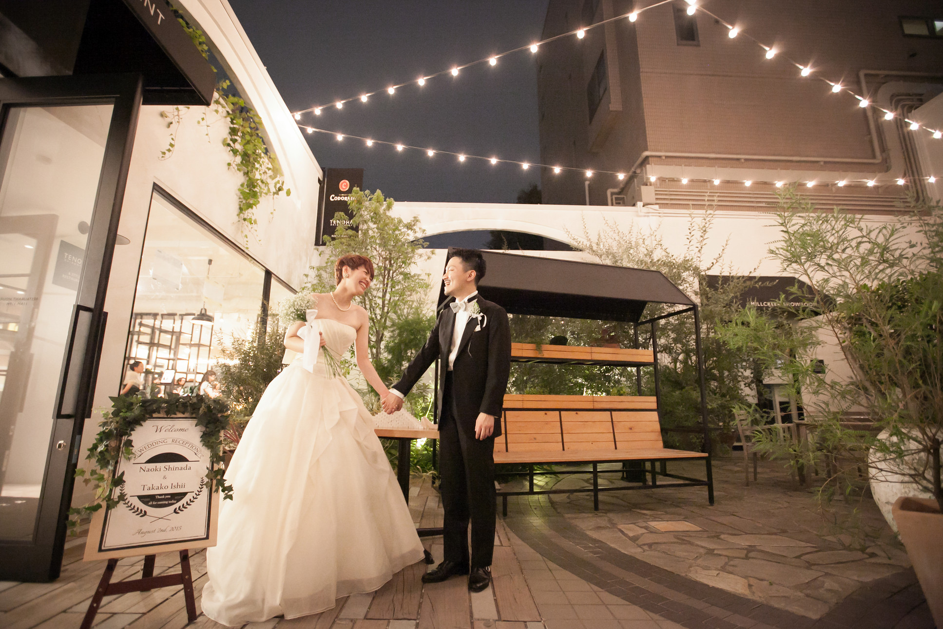 ライトアップされたモダンな建物の中で手をつなぐ新郎新婦